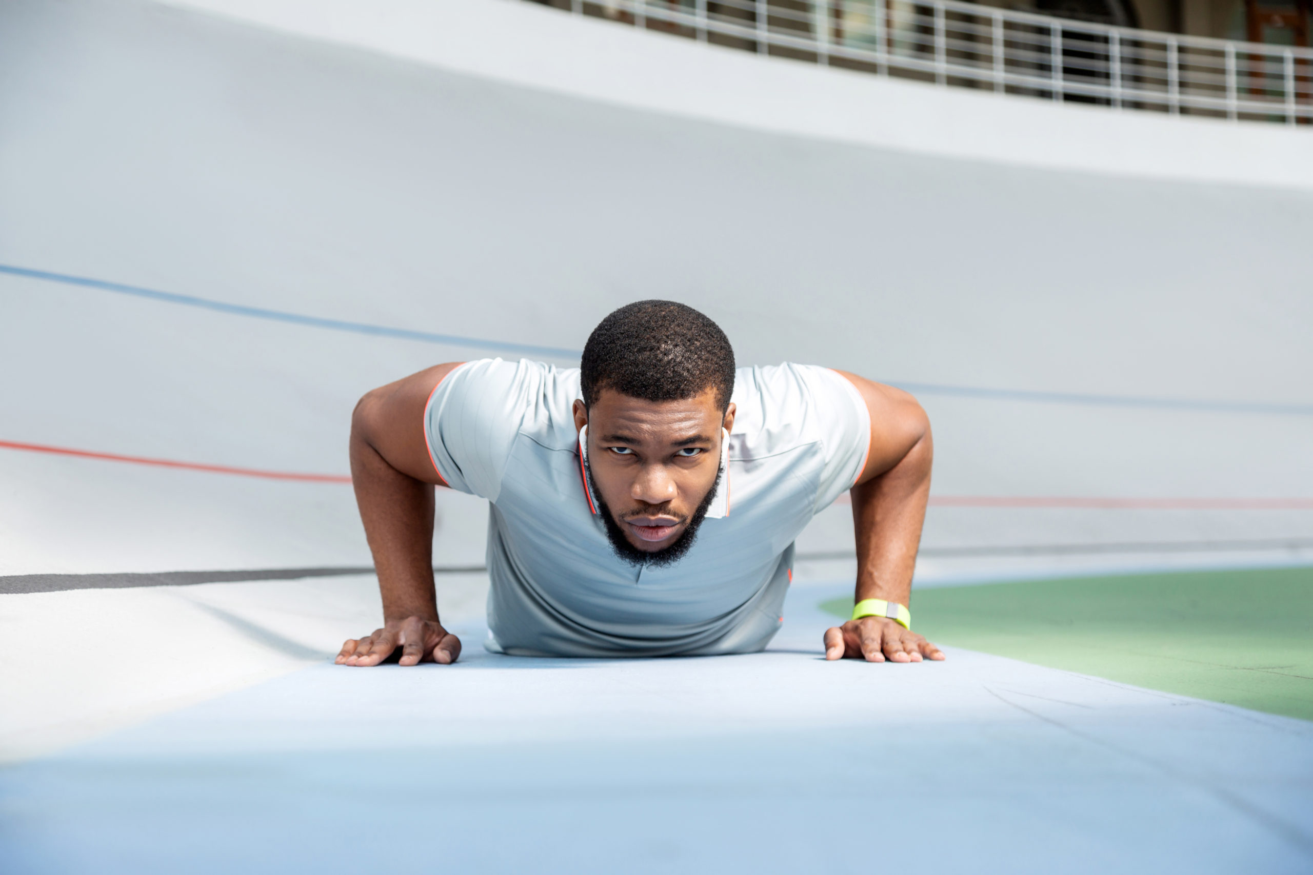 Determined athletic young man doing push-ups at the stadium while looking in front of him